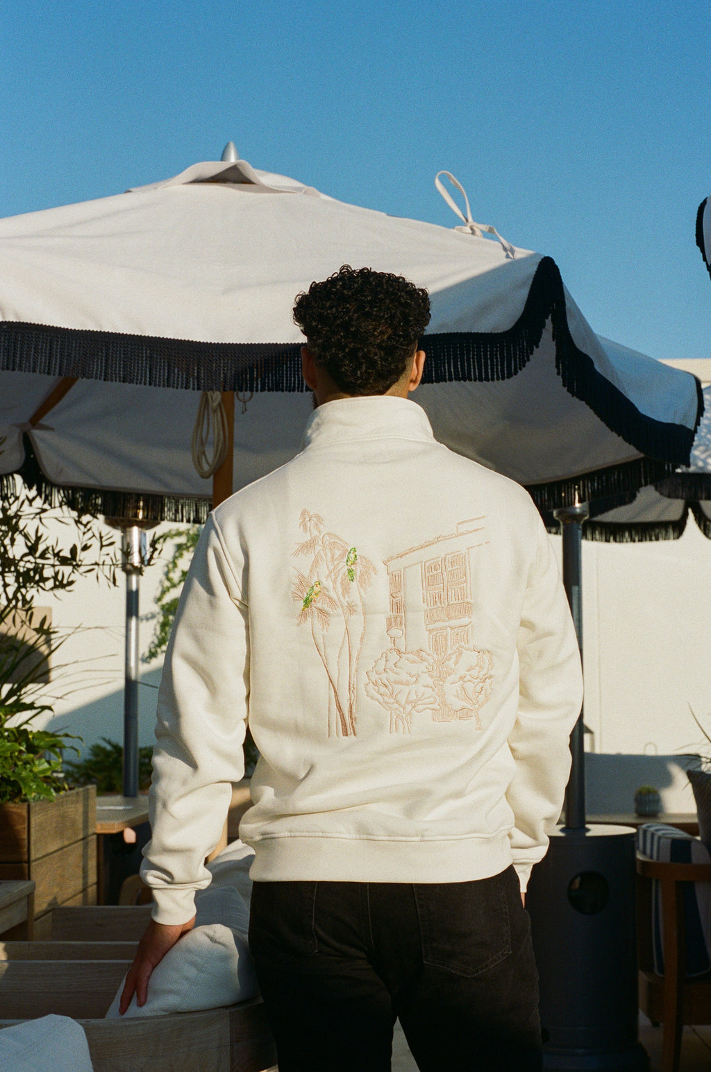 Man wearing the L'Ermitage Beverly Hills x Dinner Service NY limited merch half zip. 