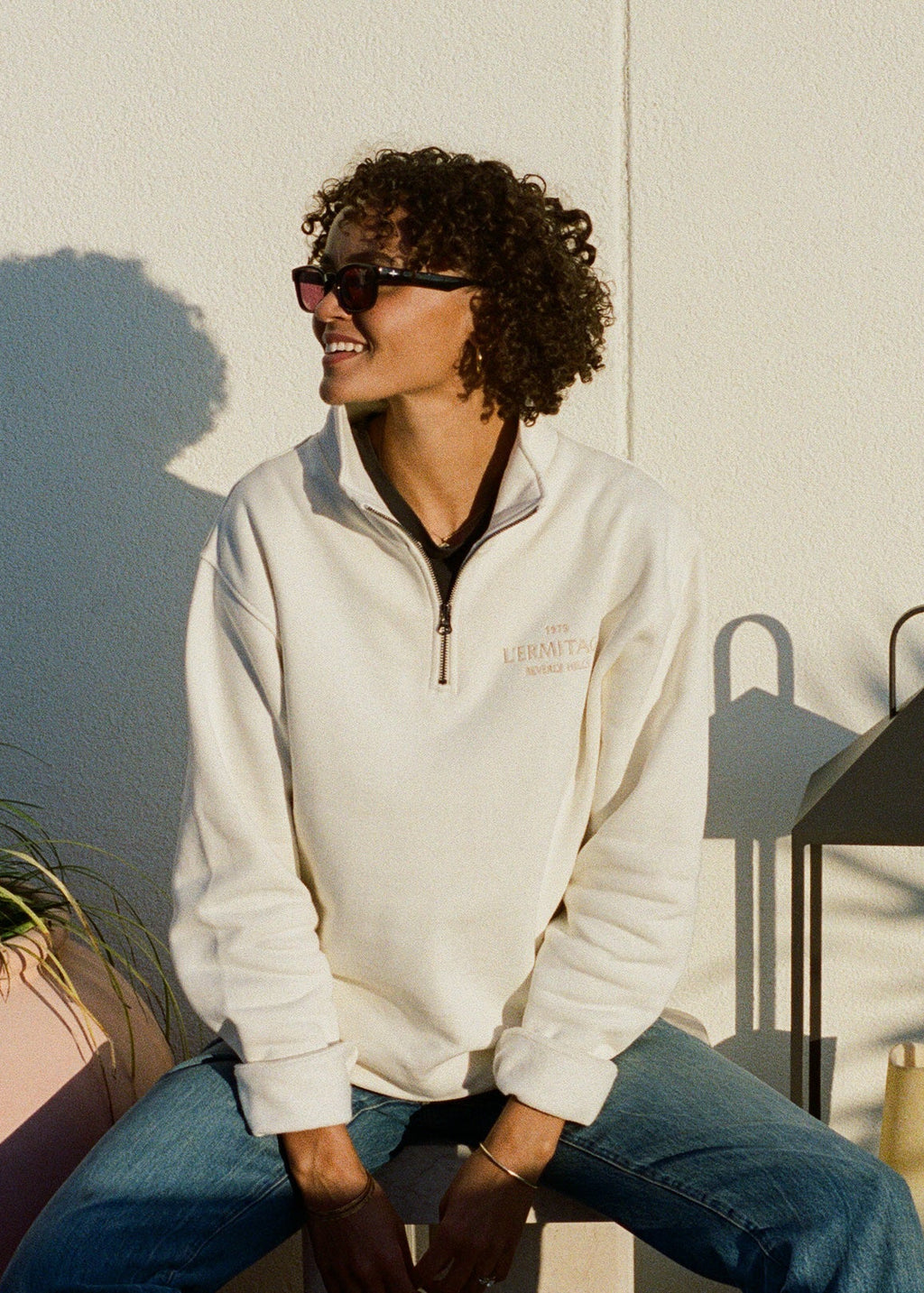 Woman wearing the L'Ermitage Beverly Hills x Dinner Service NY limited merch half zip. 